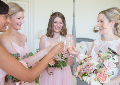 Bride in wedding dress and bridesmaids in pink dresses holding bouquets of pink and white flowers