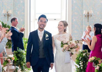 bride and groom walking down the aisle among guests after wedding ceremony in drawing room