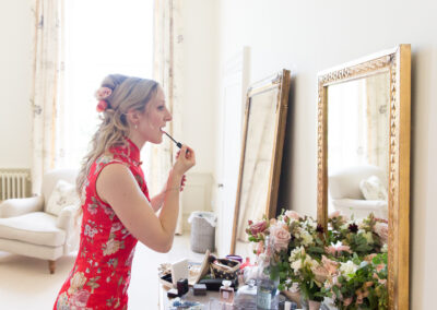 bride putting on makeup in the bridal suite wearing a red Chinese dress