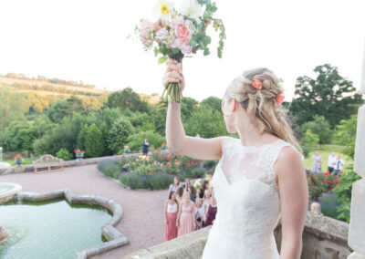 bride doing bouquet toss from balcony into rose gardens