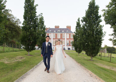 Bride and groom walking down driveway at country house wedding venue