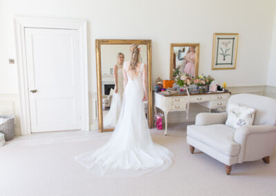 Bride in wedding dress looking in mirror in bridal suite