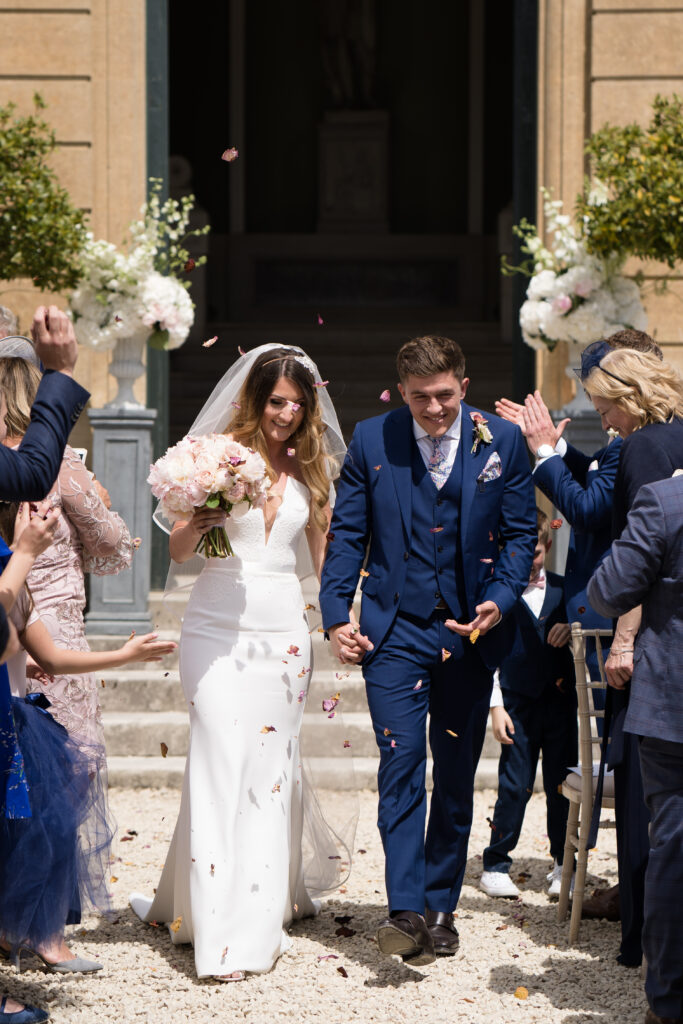 Bride and groom walking down the aisle during confetti shot at outdoor ceremony 