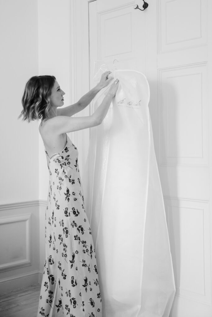 Bride checking her wedding dress which is hanging on a door.
