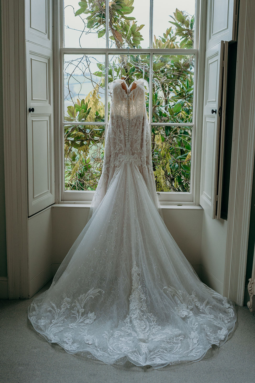 White wedding dress hanging up on window.
