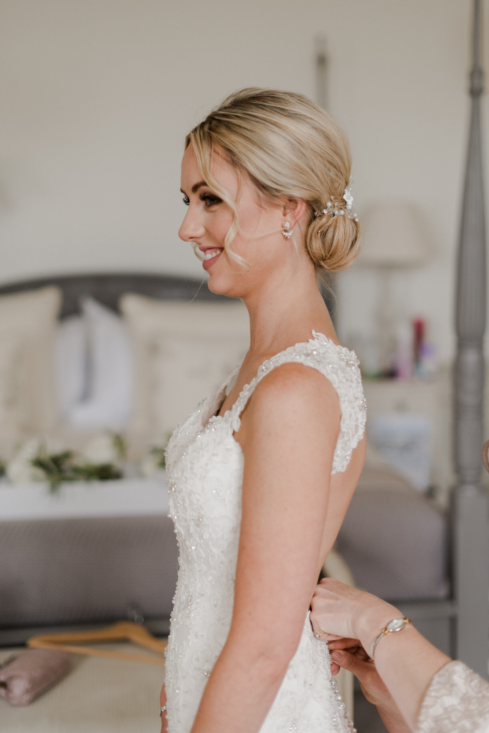 Bride standing while her wedding dress is being zipped up.