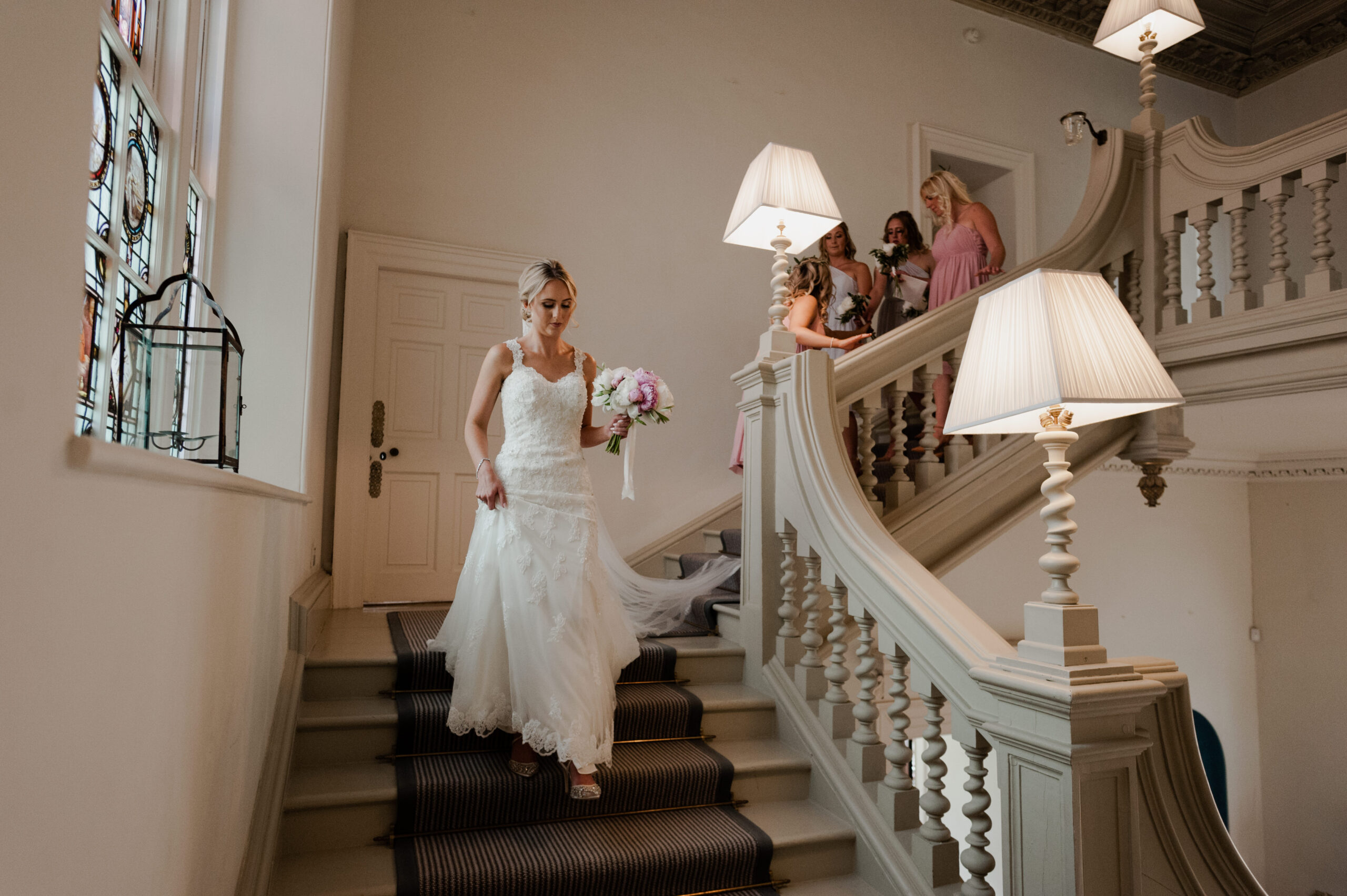 Bride wearing a white wedding dress, walking down the stairs.