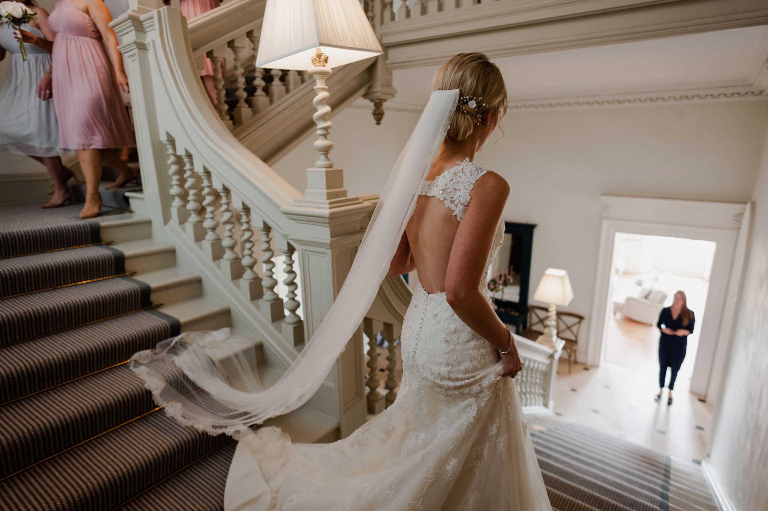 Bride wearing a white wedding dress, walking down the stairs.