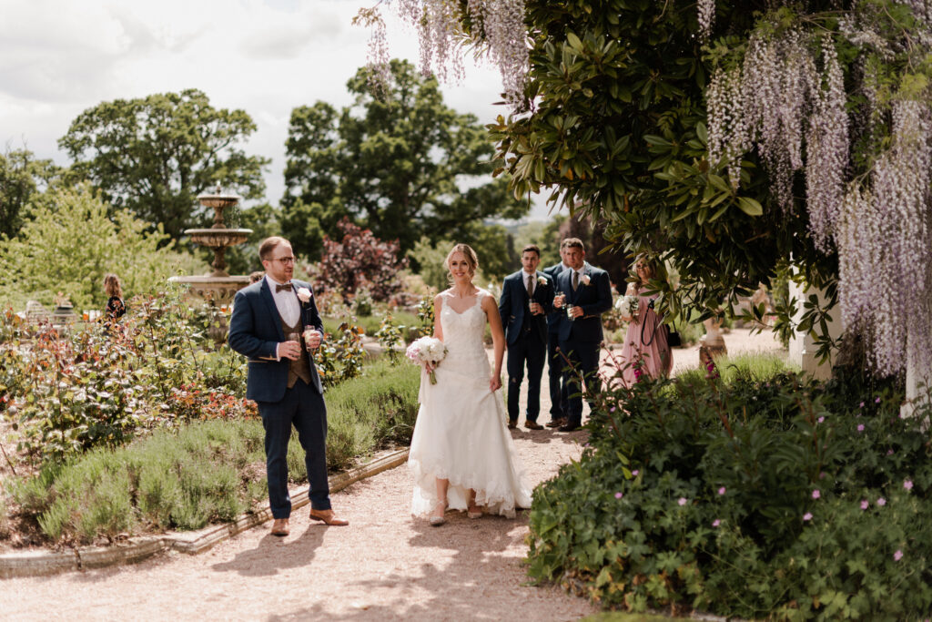 Bride and bridal party walking through gardens.