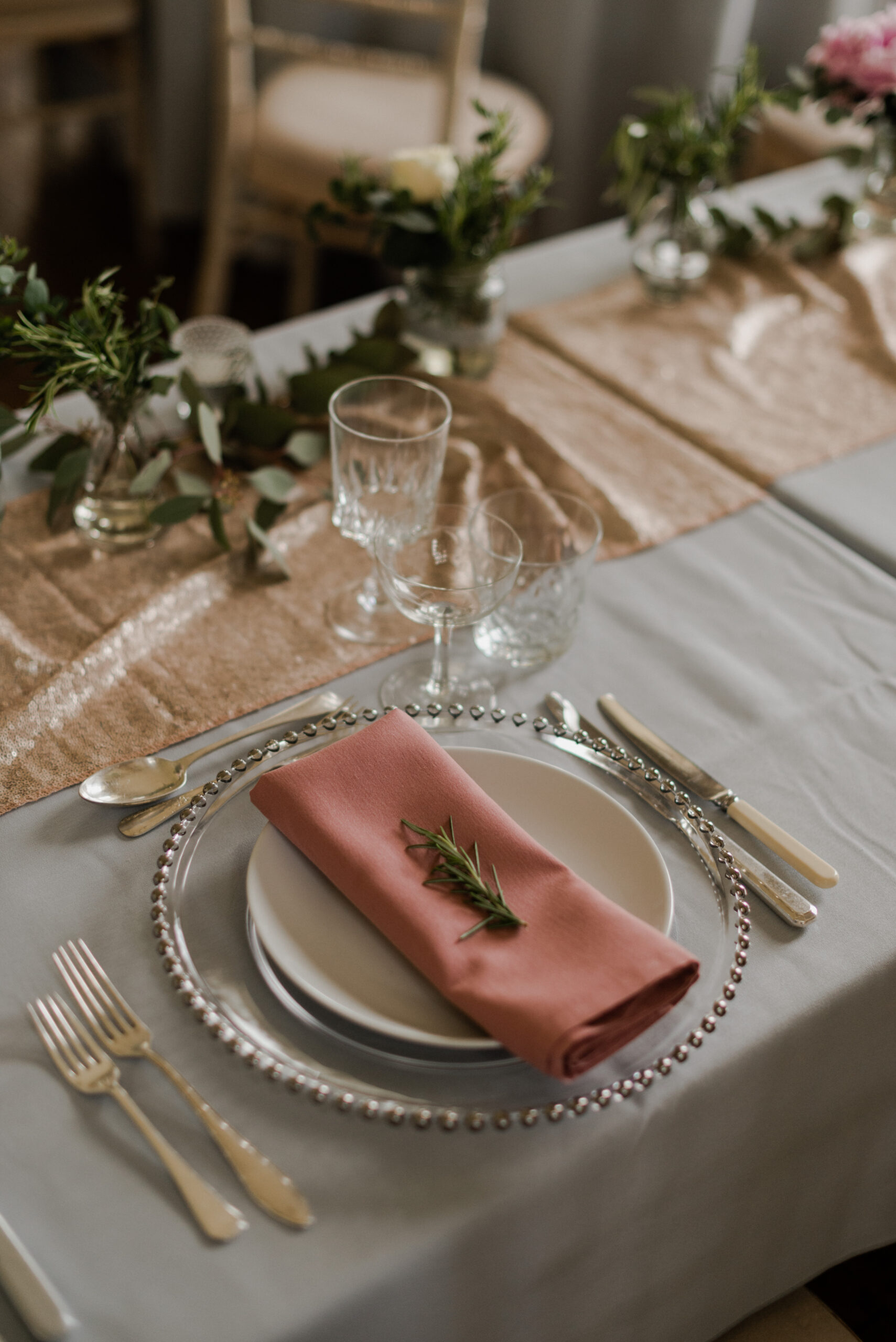 Wedding reception table setting with plates, napkin, cutlery and glassware.