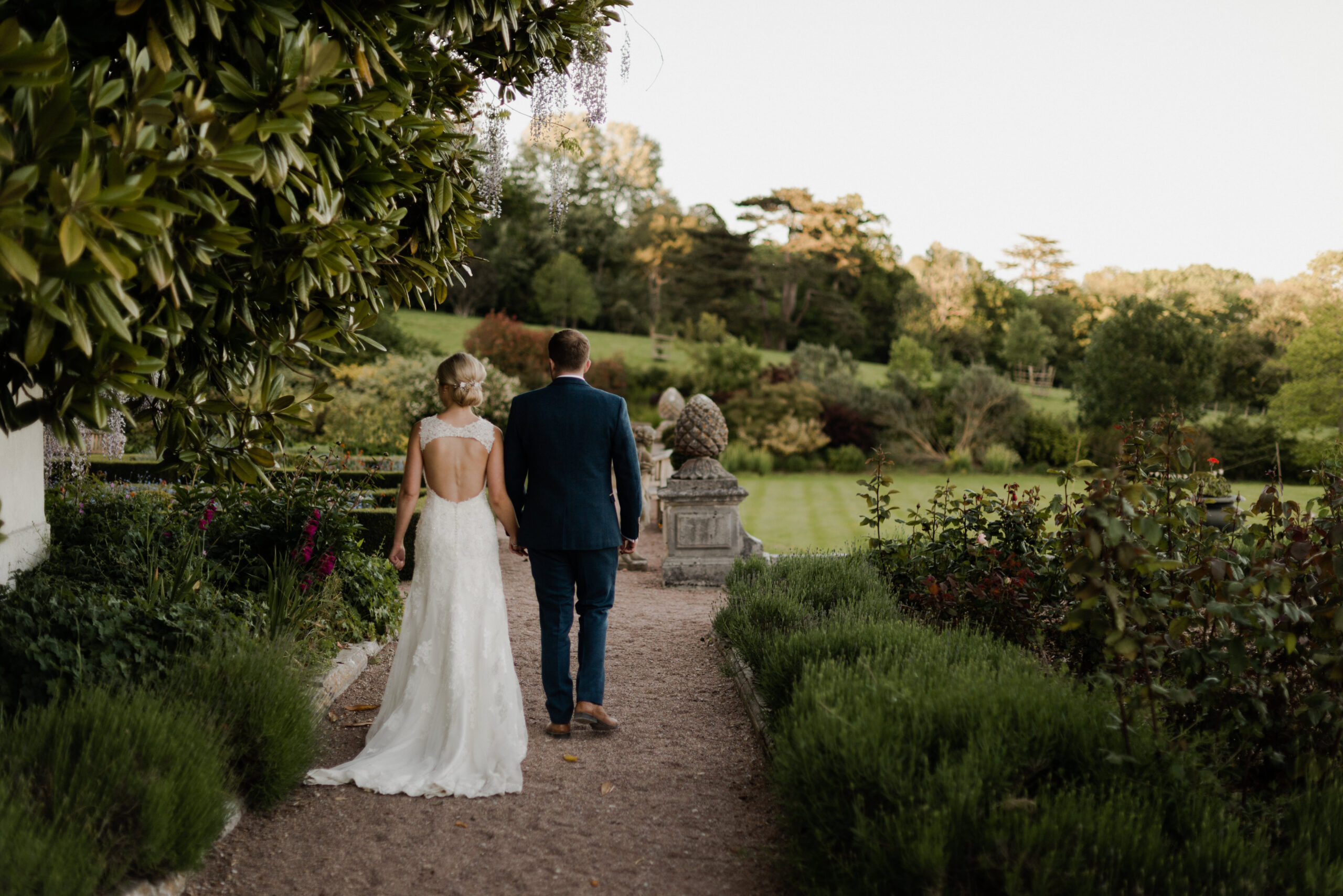 Bride and groom walking in English country house gardens.