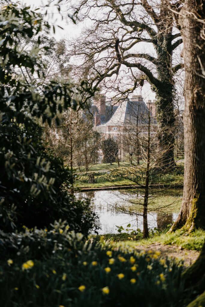 English country house behind pond, in spring.