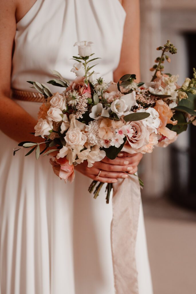 Bride holding bouquet of pink pastel wedding flowers.