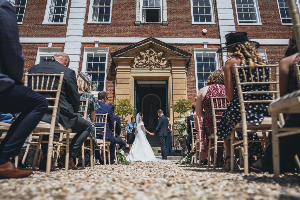Bride and groom saying vows in wedding ceremony which is outdoors.