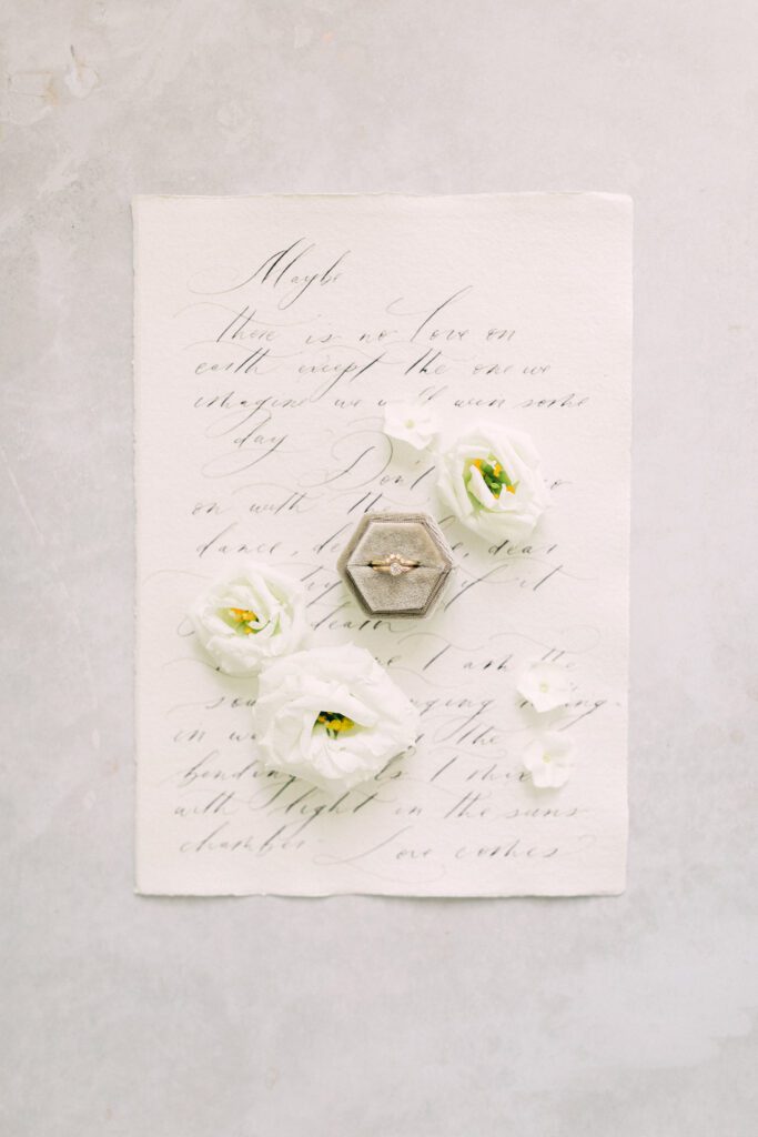 Bespoke calligraphy wedding stationery, with white flowers and wedding ring.