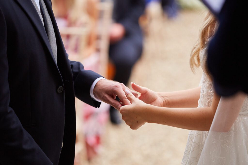 Bride putting ring on groom's finger during wedding ceremony.