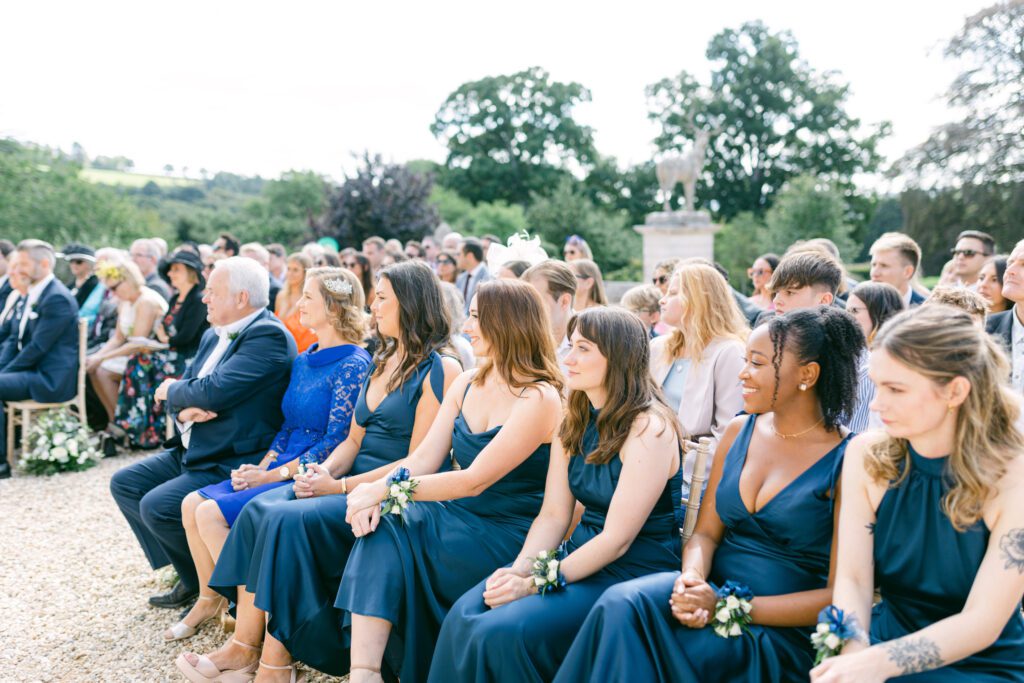 Wedding guests listening to children's wedding readings, during outdoor wedding ceremony in Devon.