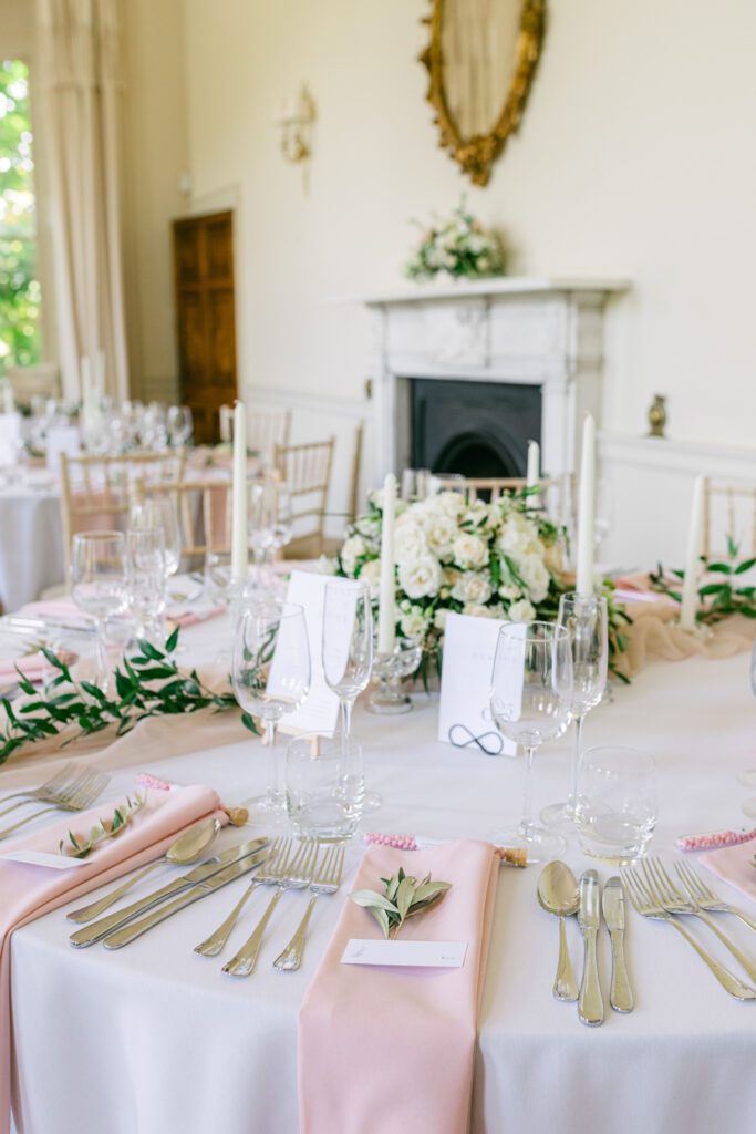 Luxury reception place settings with pastel colours and roses, at black tie wedding.