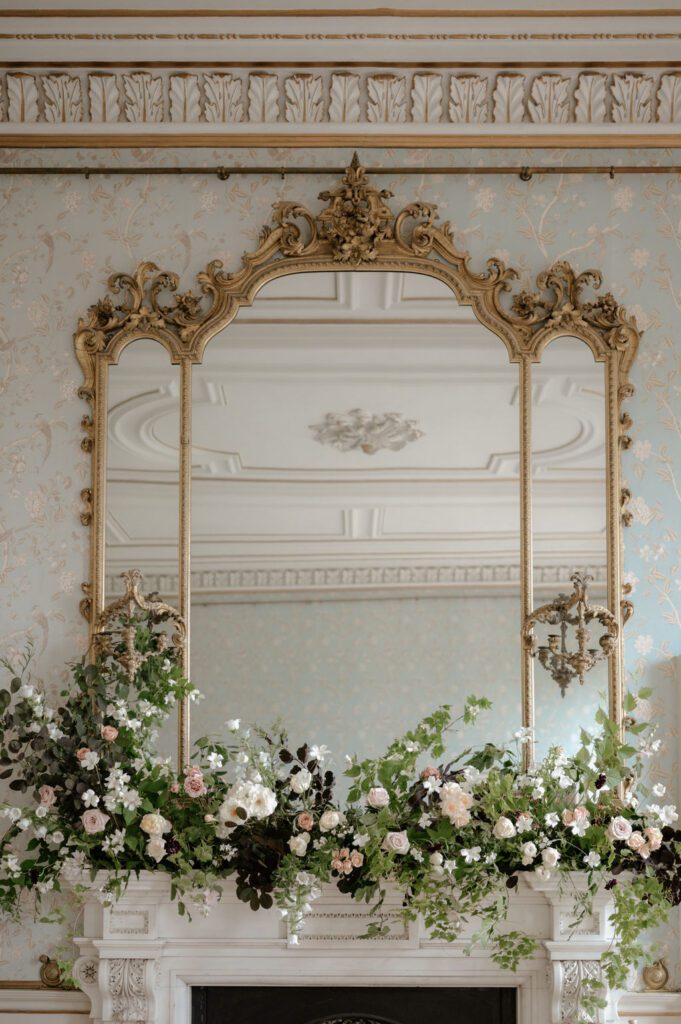 Floral arrangement on mantelpiece under mirror, for luxury wedding in Devon.