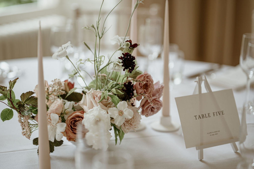 Wedding centrepiece of blush and maroon wedding flowers.