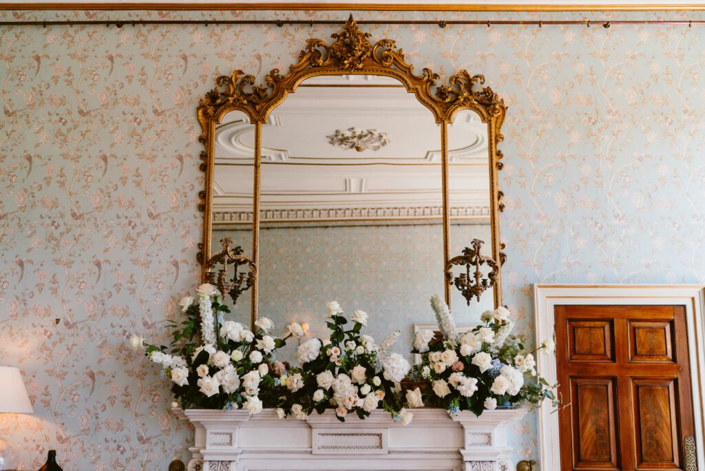 Luxury wedding flowers decorate a mantlepiece at a historic wedding venue in Devon.