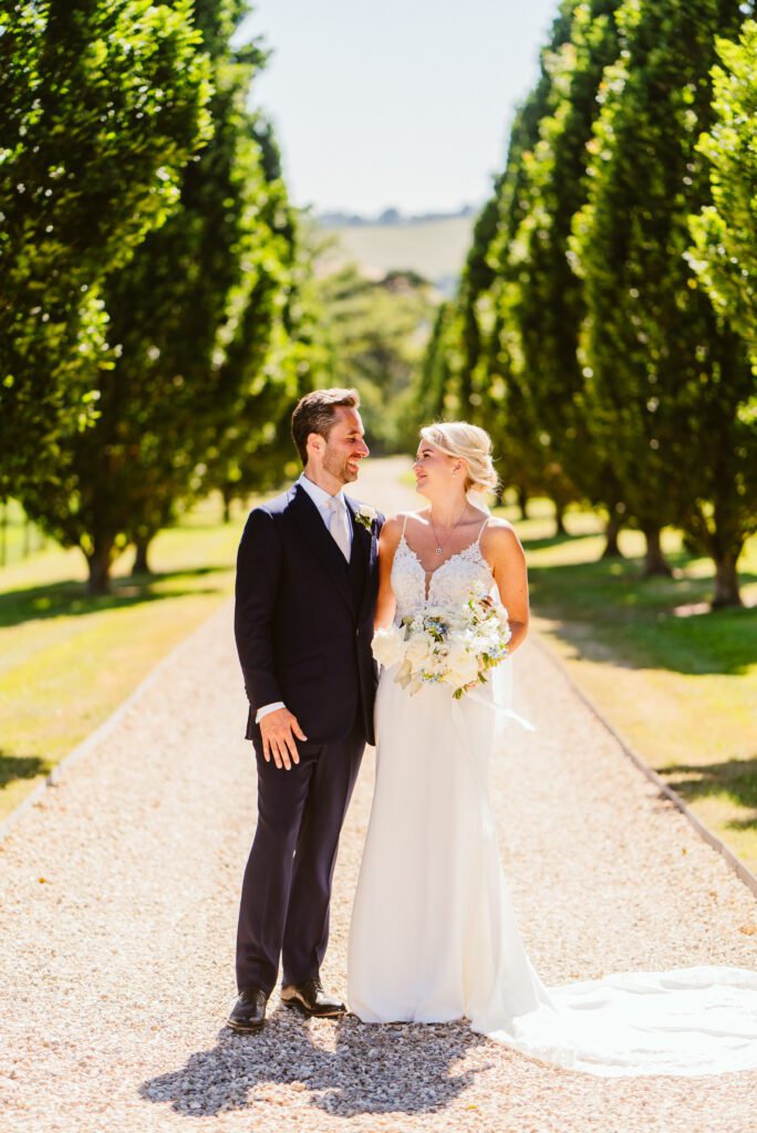 A couple pose for couple photos on a tree lined driveway at Pynes House