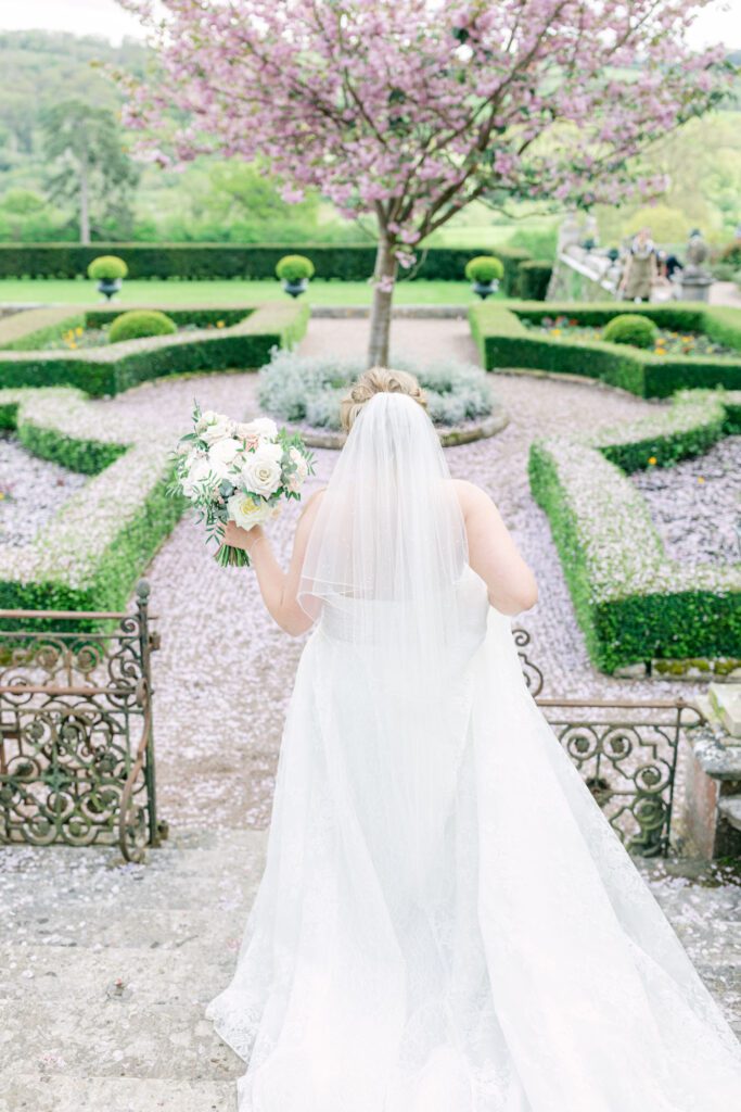 A bride walks through an English country house parterre, during an English country garden wedding.