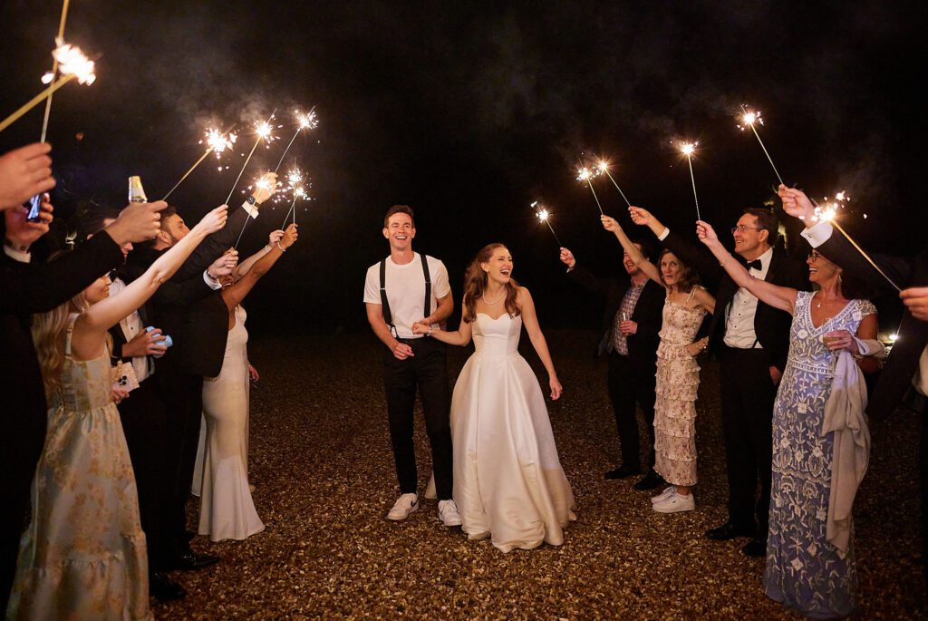 A bride and groom enjoy a sparkler arch, at an outdoor wedding venue