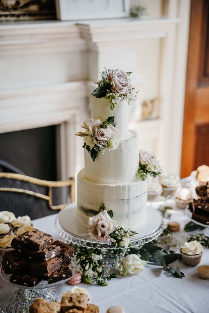 A cake surrounded by sweet treats at a wedding cake table