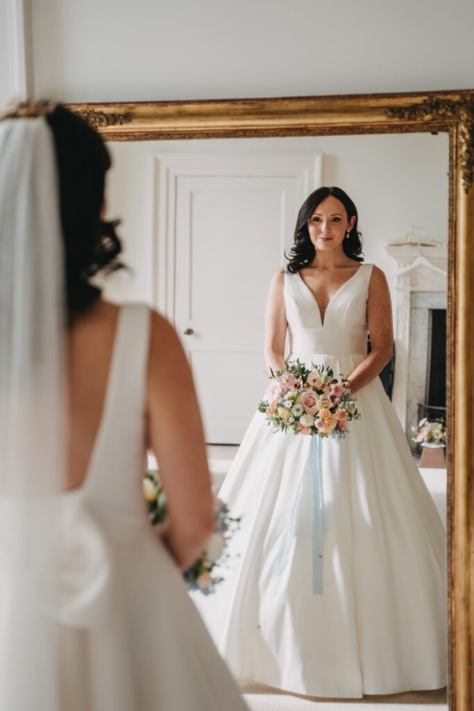 A bride admires her dress in the mirror, for wedding planning checklist inspiration